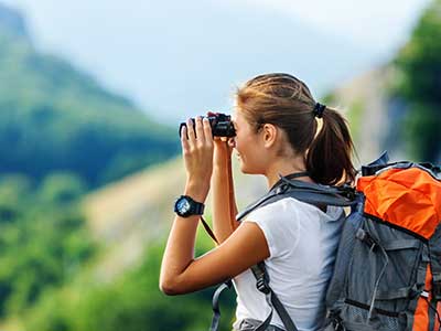 woman using binoculars on hike
